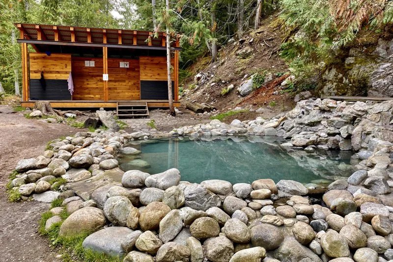 Rock-lined main pool and timber changing building at Halfway River Hot Springs