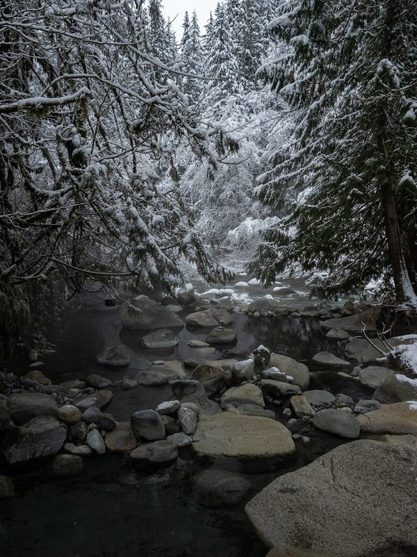 Rock-lined thermal pools in snowy forest at Sloquet Hot Springs (archive photograph)